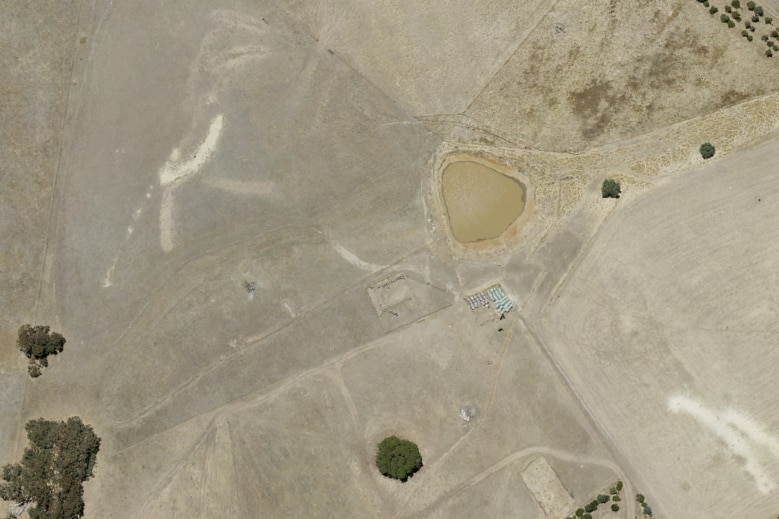 Air photo of a single dam, surrounded by dry soil and some trees.