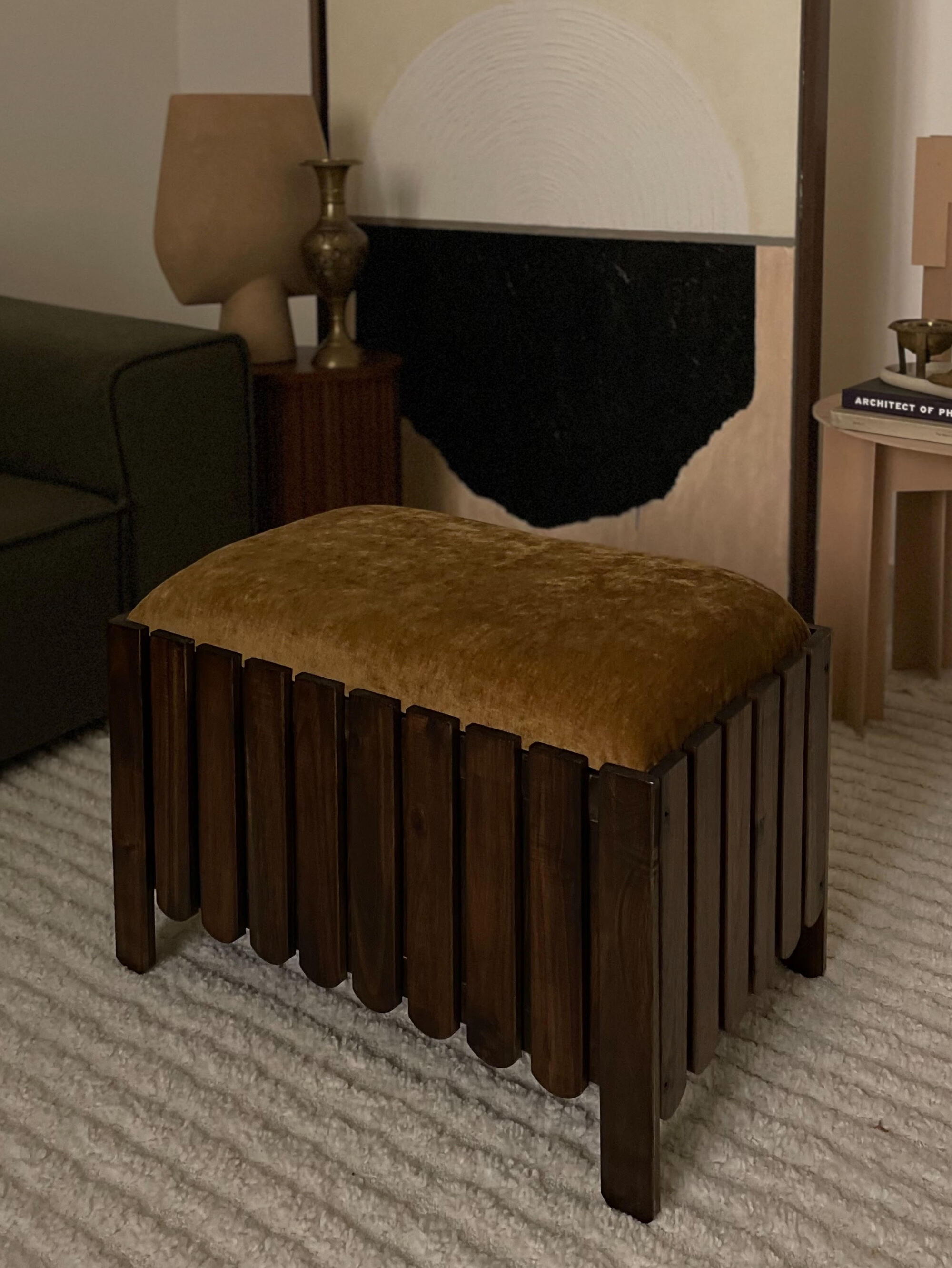 A dark wooden flower box with broken edges that was turned into a stool/Ottoman. The pillow above is an ocher yellow fabric.