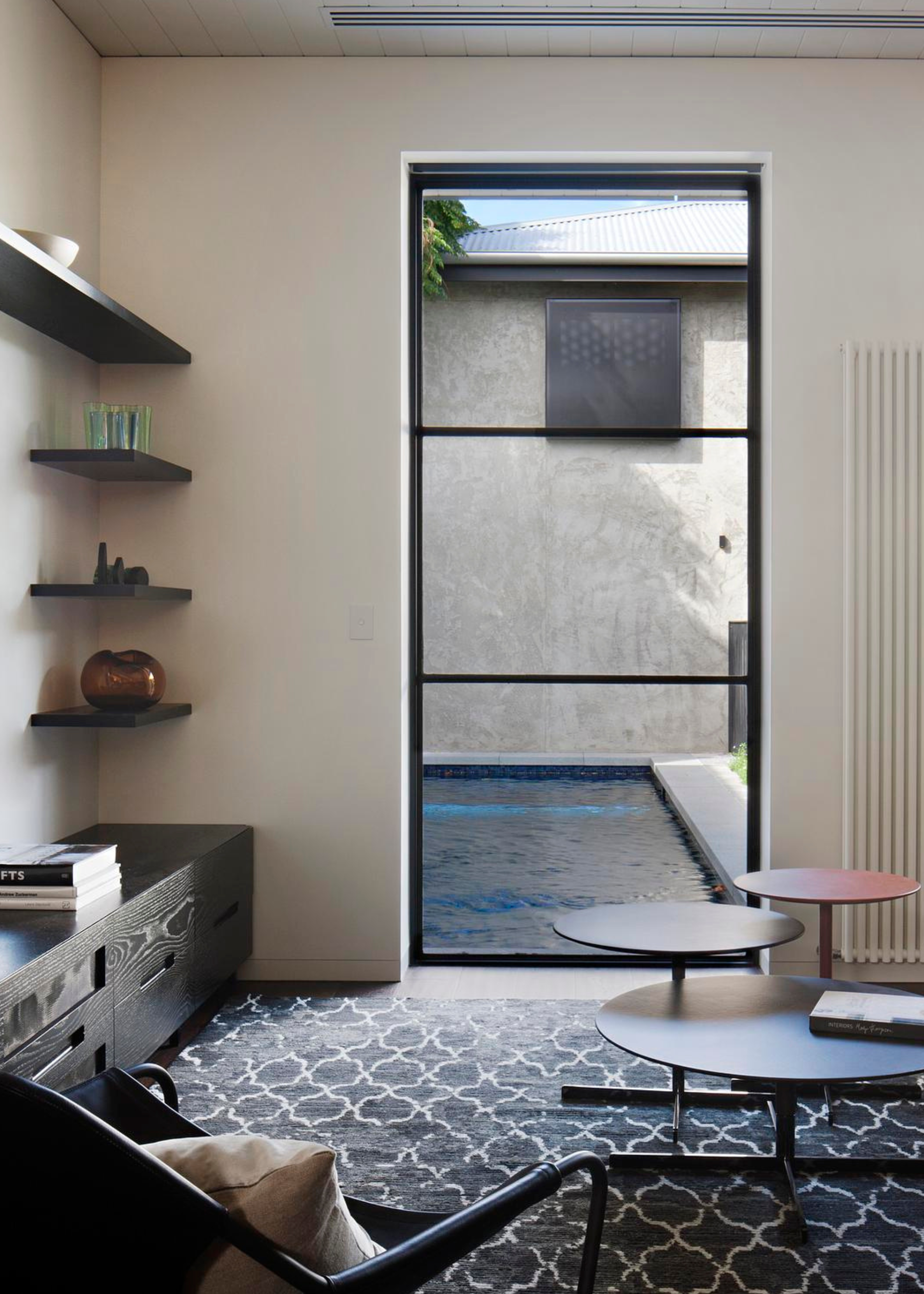 A living room with a large window that looks directly at a swimming pool