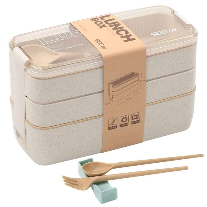 Three stacked rectangular beige lunch boxes with a clear lid and a brown paper label next to a wooden fork and a spoon, which rests back to school on two blue stick holders.