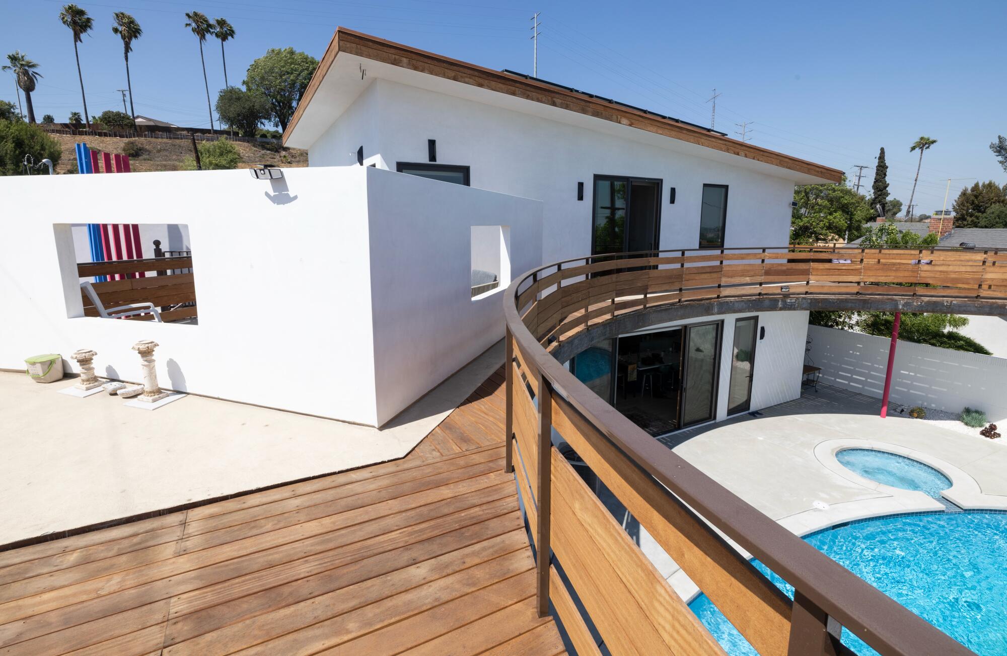 A second story balcony that bends around a swimming pool.