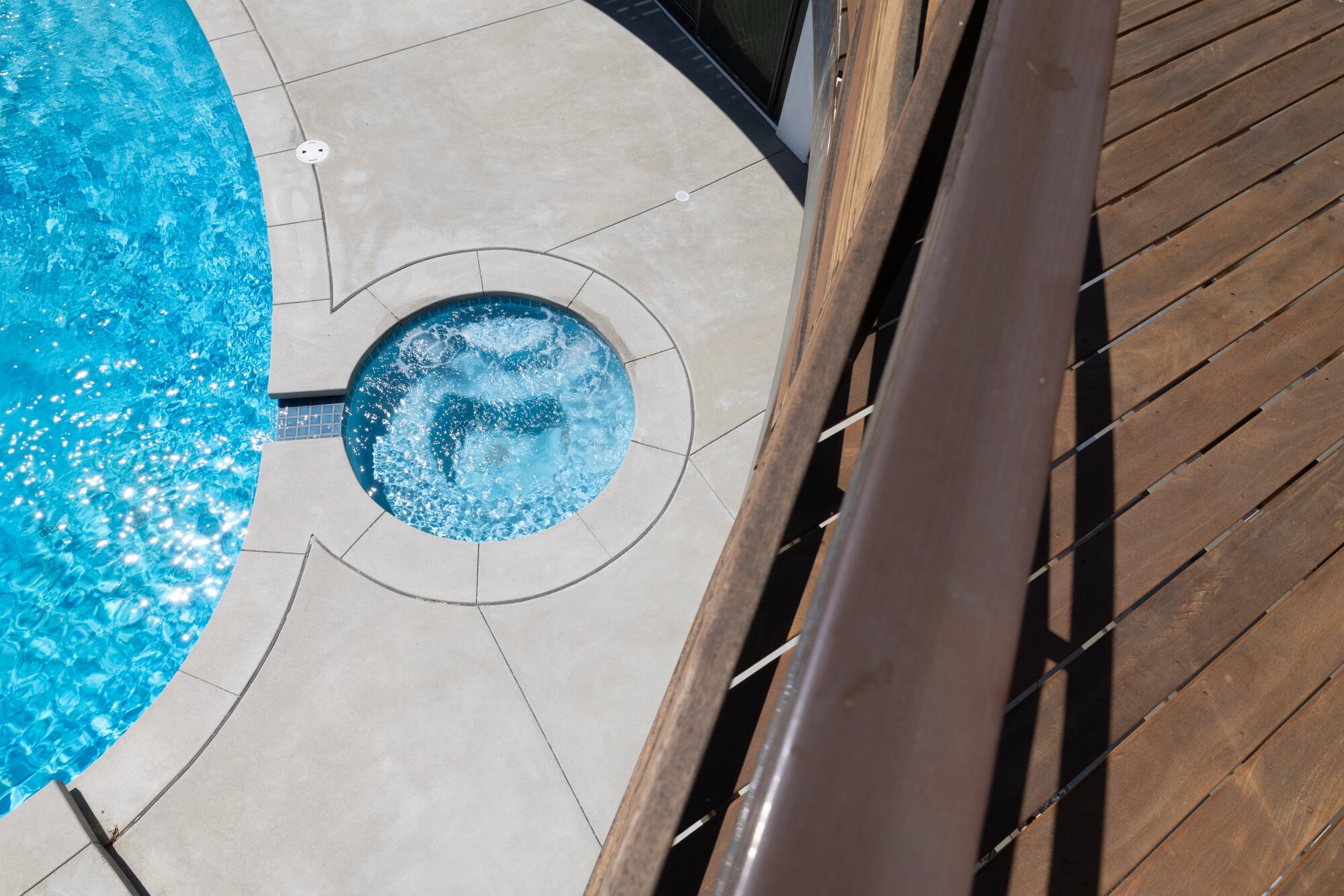 A swimming pool, on the left, as viewed from a deck on the second floor.