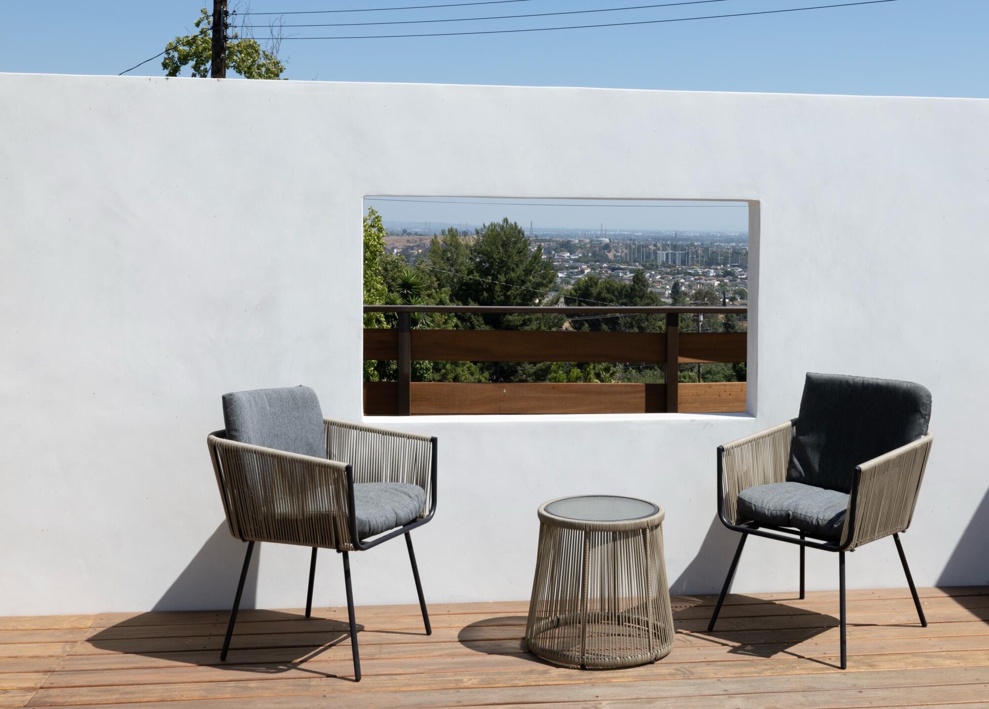 Two chairs rest with a window in front of a partial height wall.