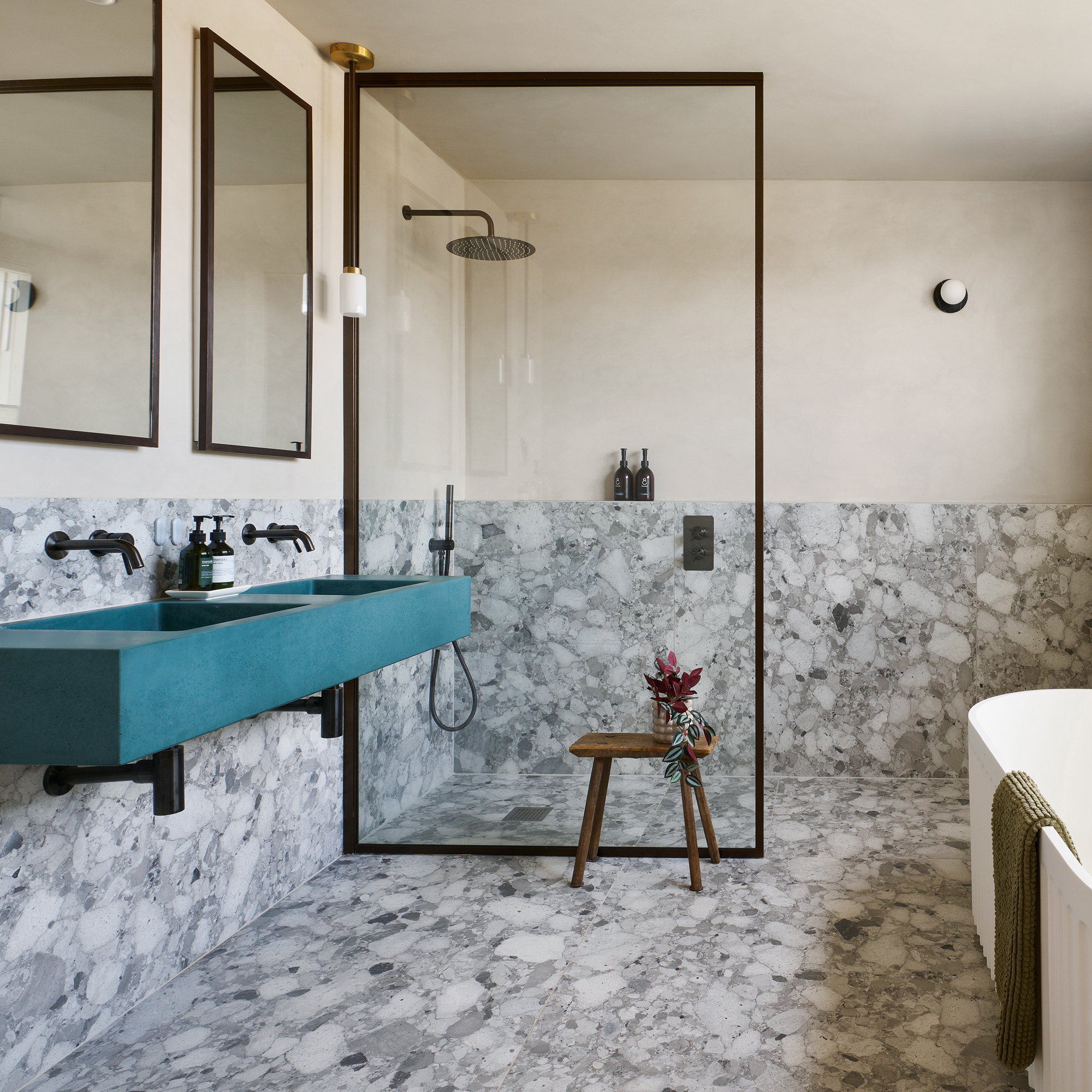 Bathroom with a glass shower plate, stone floors and blue/green double pool