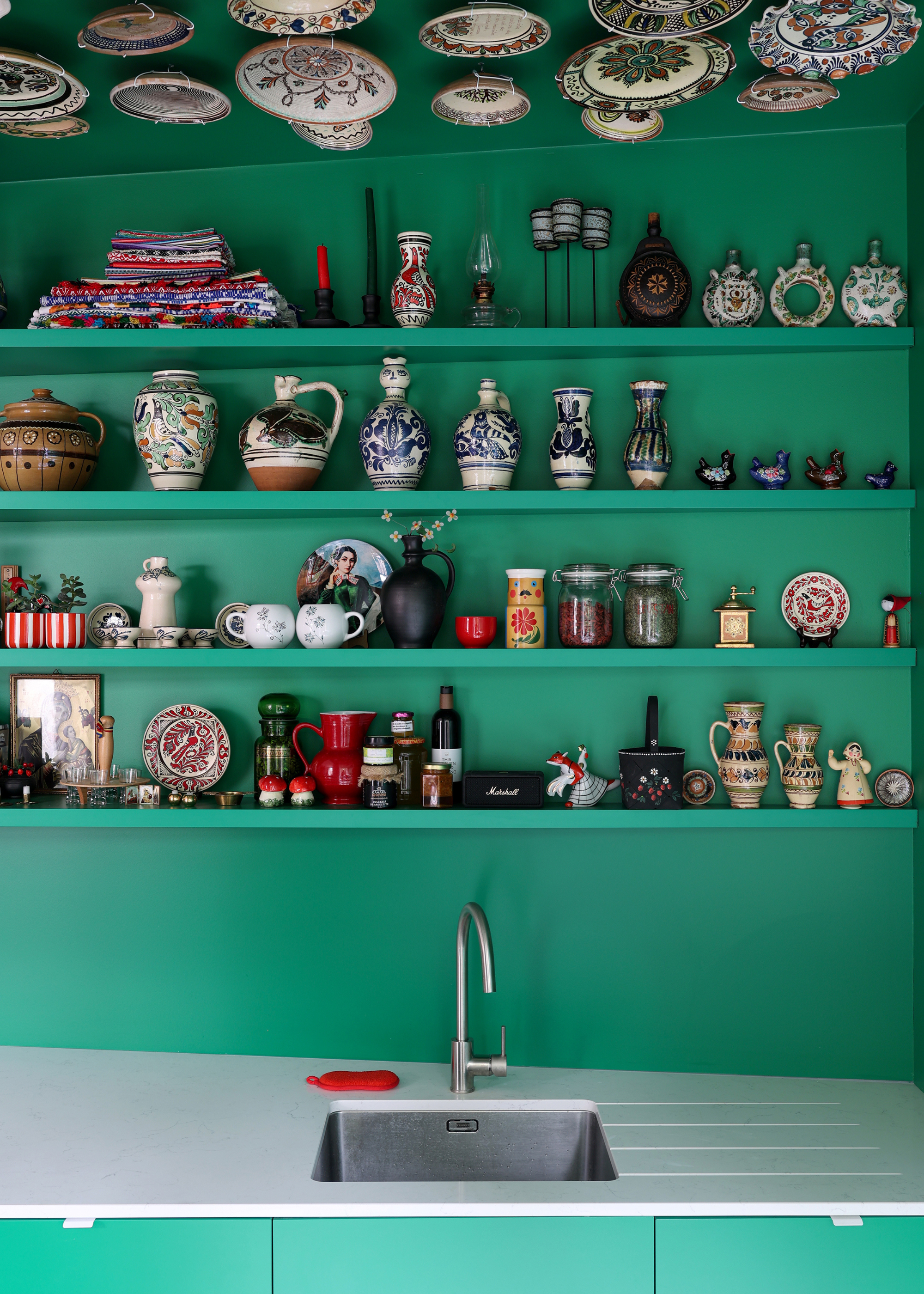 Close up of a green kitchen with open shelves with ceramics and Nick Nacks