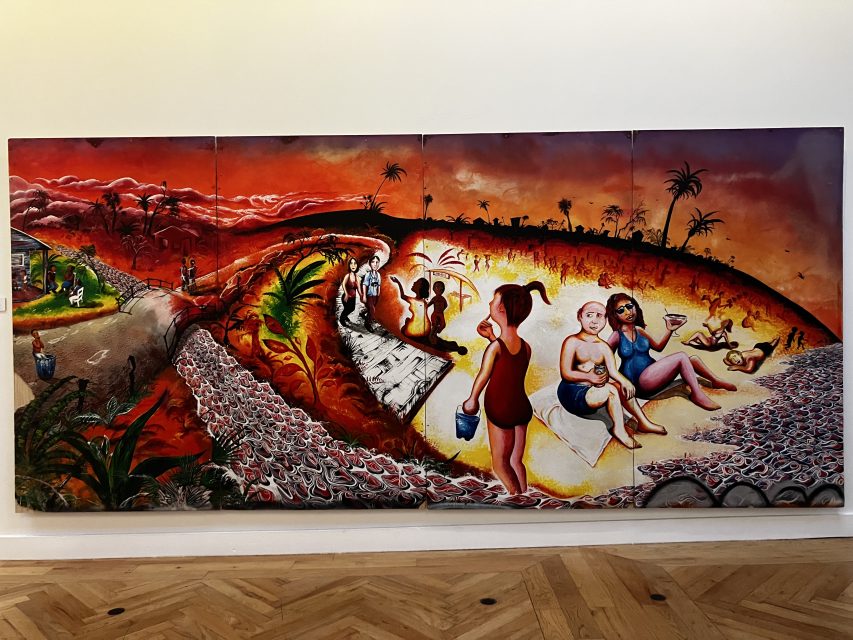 A colorful mural shows a shared landscape: one side shows poverty and struggle, while other people showing themselves on a beach under a bright sky.