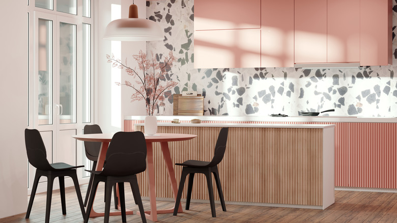 A kitchen with bloated pink cupboards and a terrazzo backplash