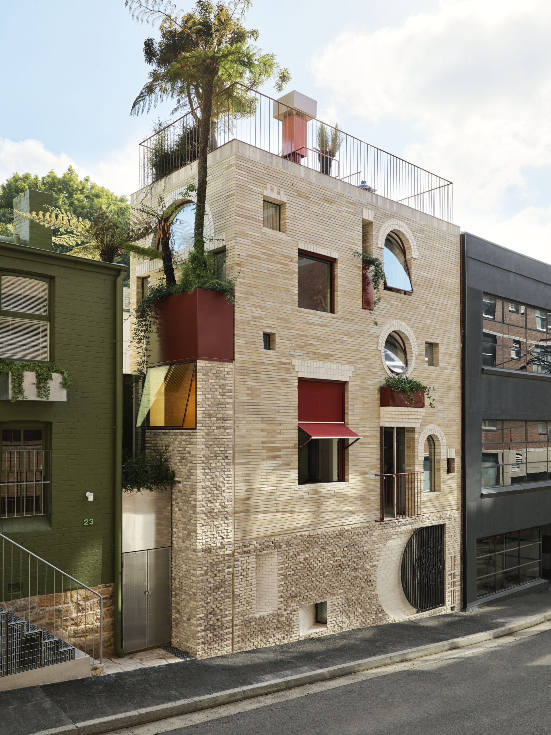 A cream -colored house with a collection of different and shaped windows and a roof garden.