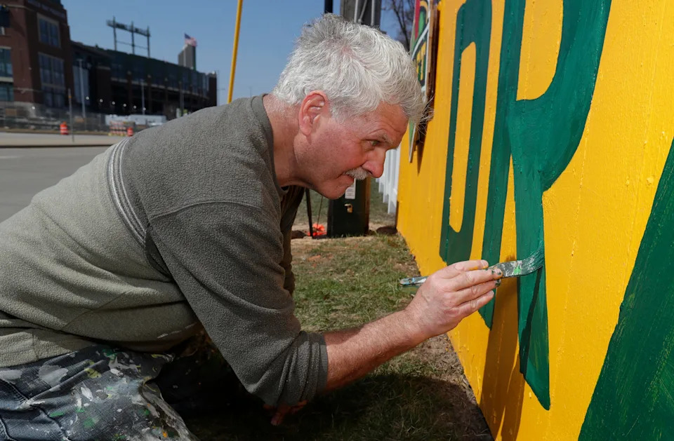 Christopher Handler paints the fence in the 1167 Shadow Lane on April 11th in Green Bay and celebrates the NFL design of 2025 in Lambeau Field.