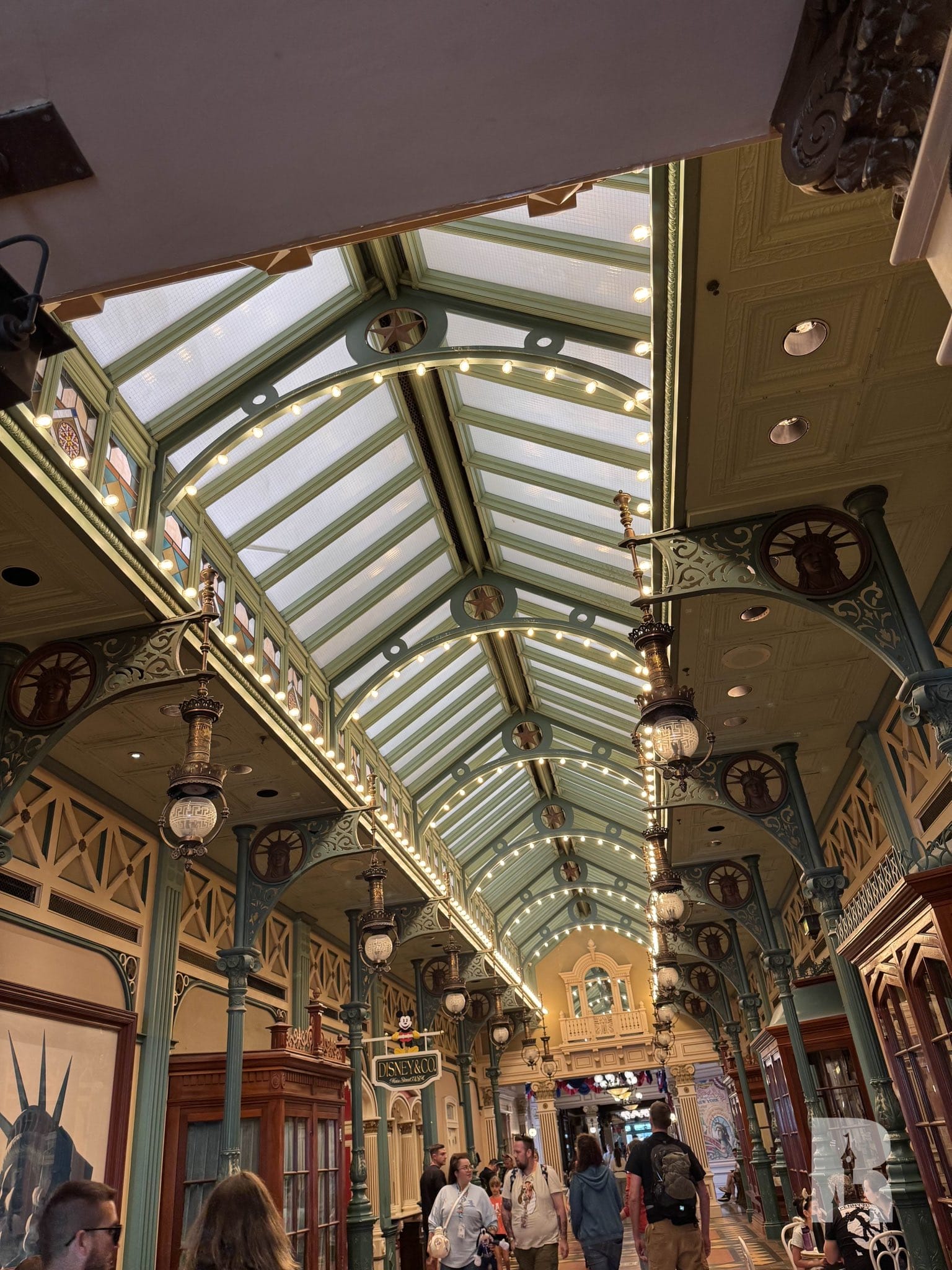 One in the glass roof in the interior with skylights, green metal beams, vintage lanterns and people who walk under the ceiling.