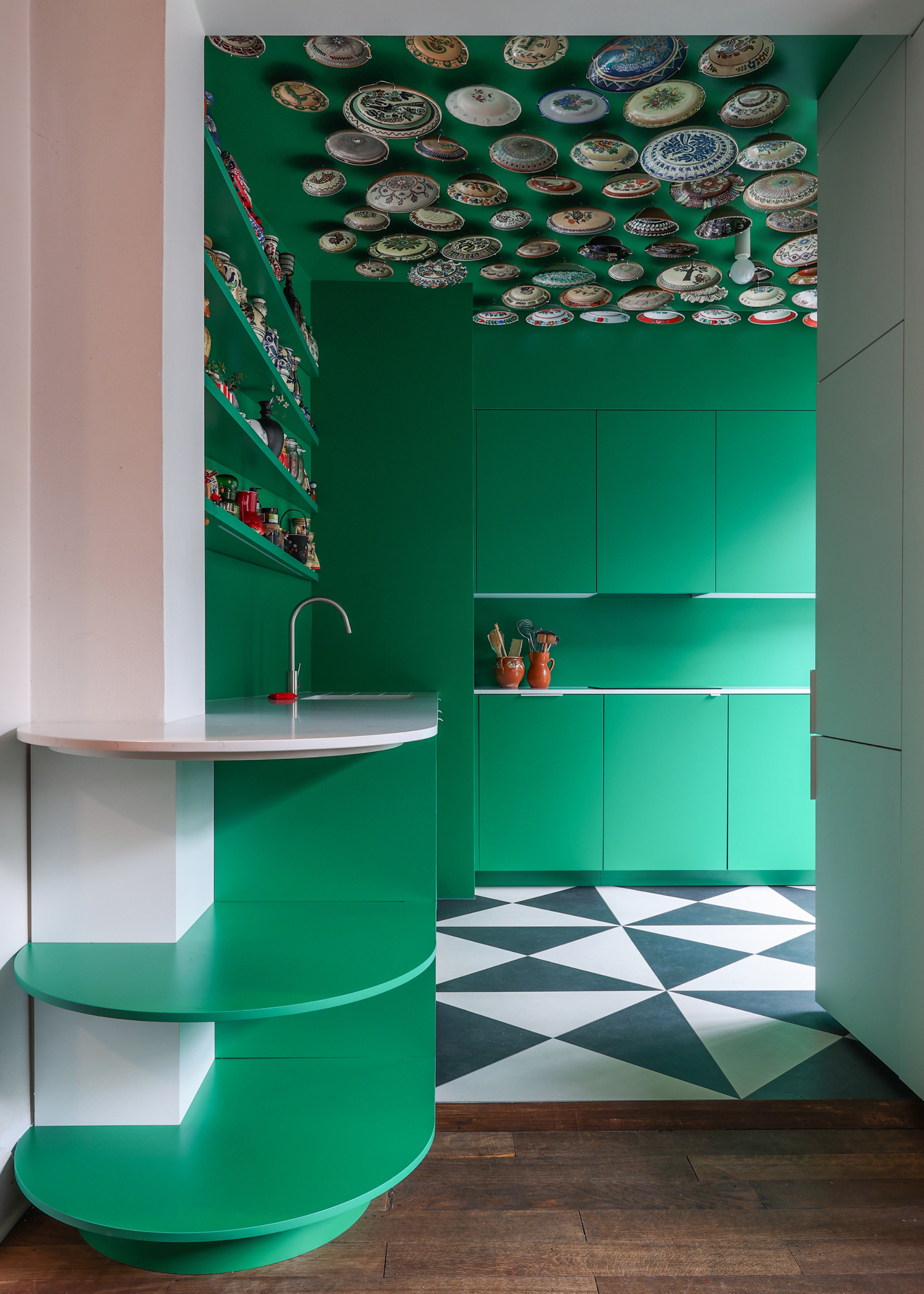A look into a small kitchen color, the green, black and white floor coverings and plates soaked on the ceiling