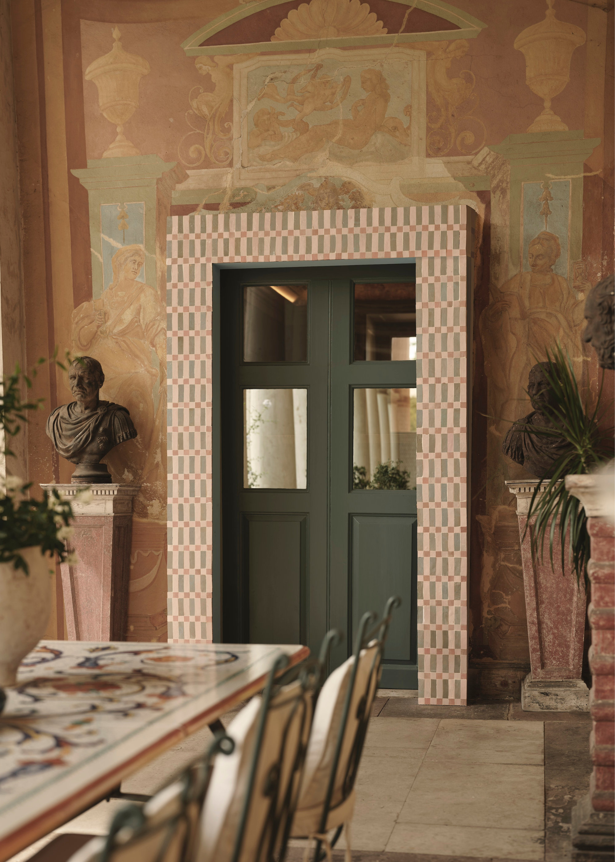 A tiled door and a dramatic and elaborate room with busts and marble and fresco walls