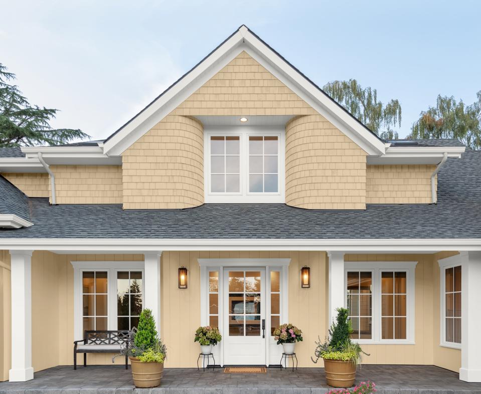 Traditional two -story home with butter yellow color and white equipment.