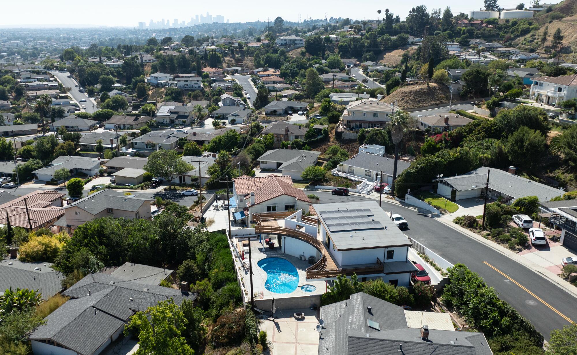A drone recording of a pool house with Downtown Los Angeles in the distance.