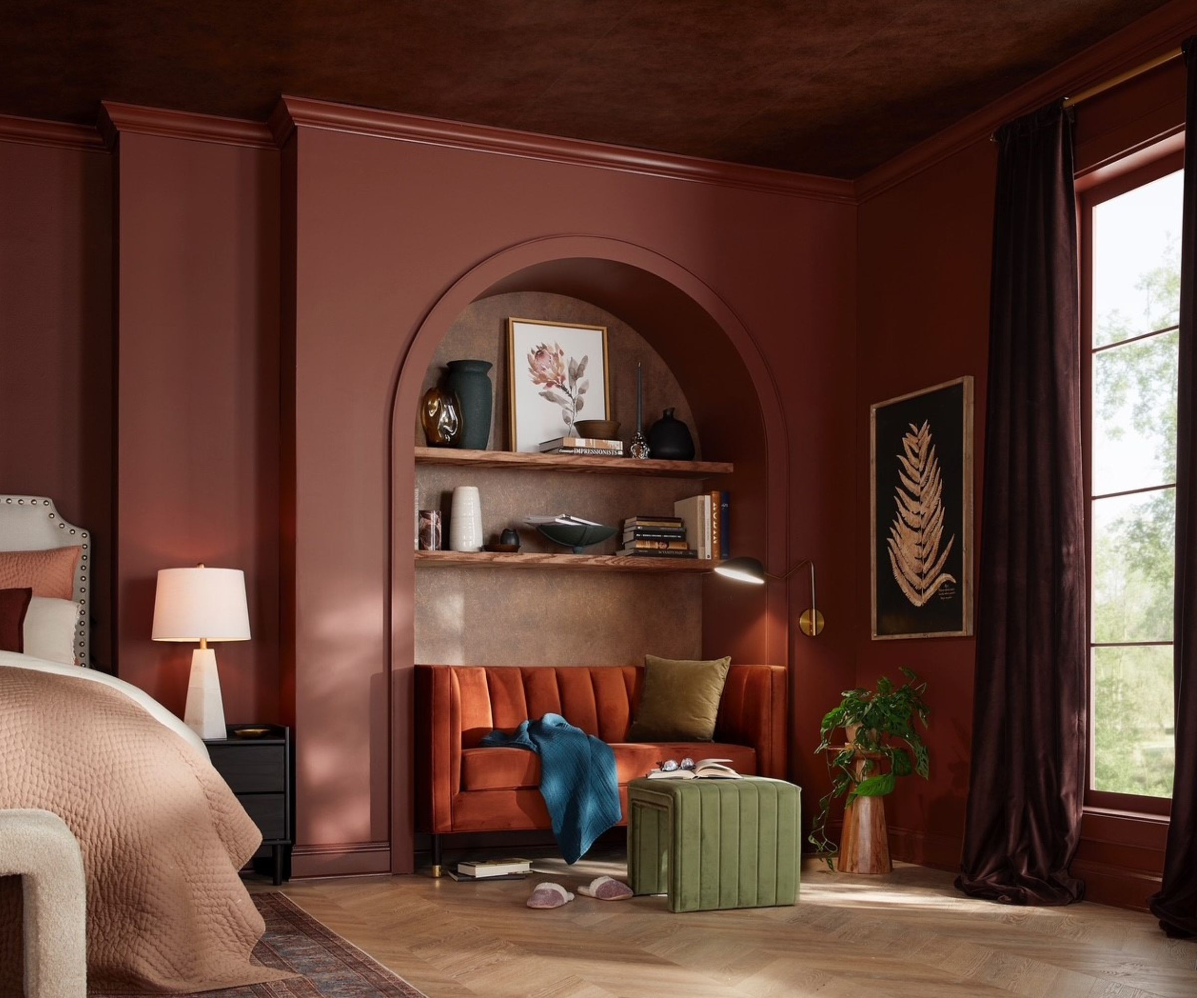 Mahogany red painted bedroom with a vaulted bookshelf and read corners with orange sofa and green ottoman and large window
