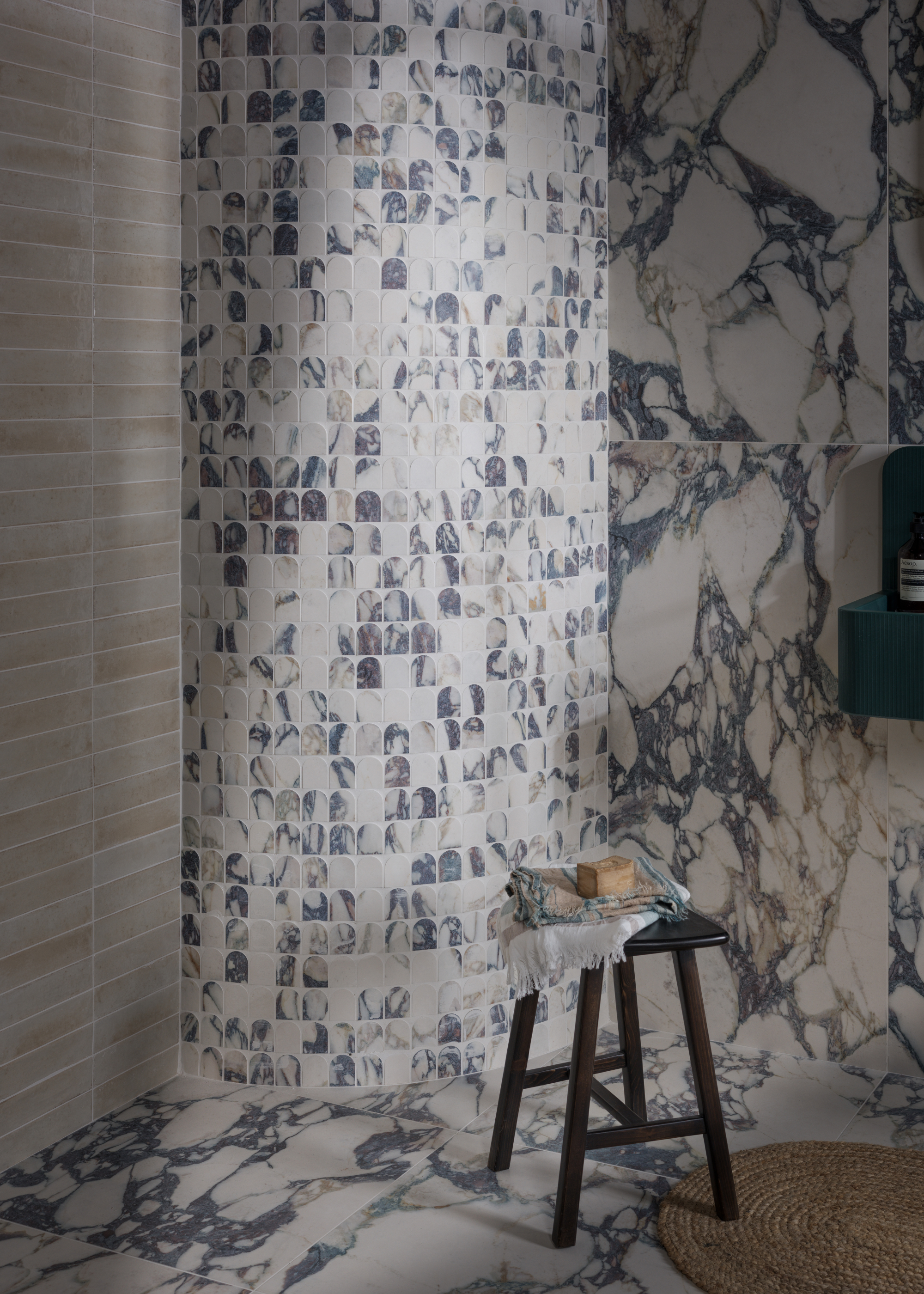 A marble -flying bathroom with a curved wall in small tiles and large format marble tiles over the rest of the room