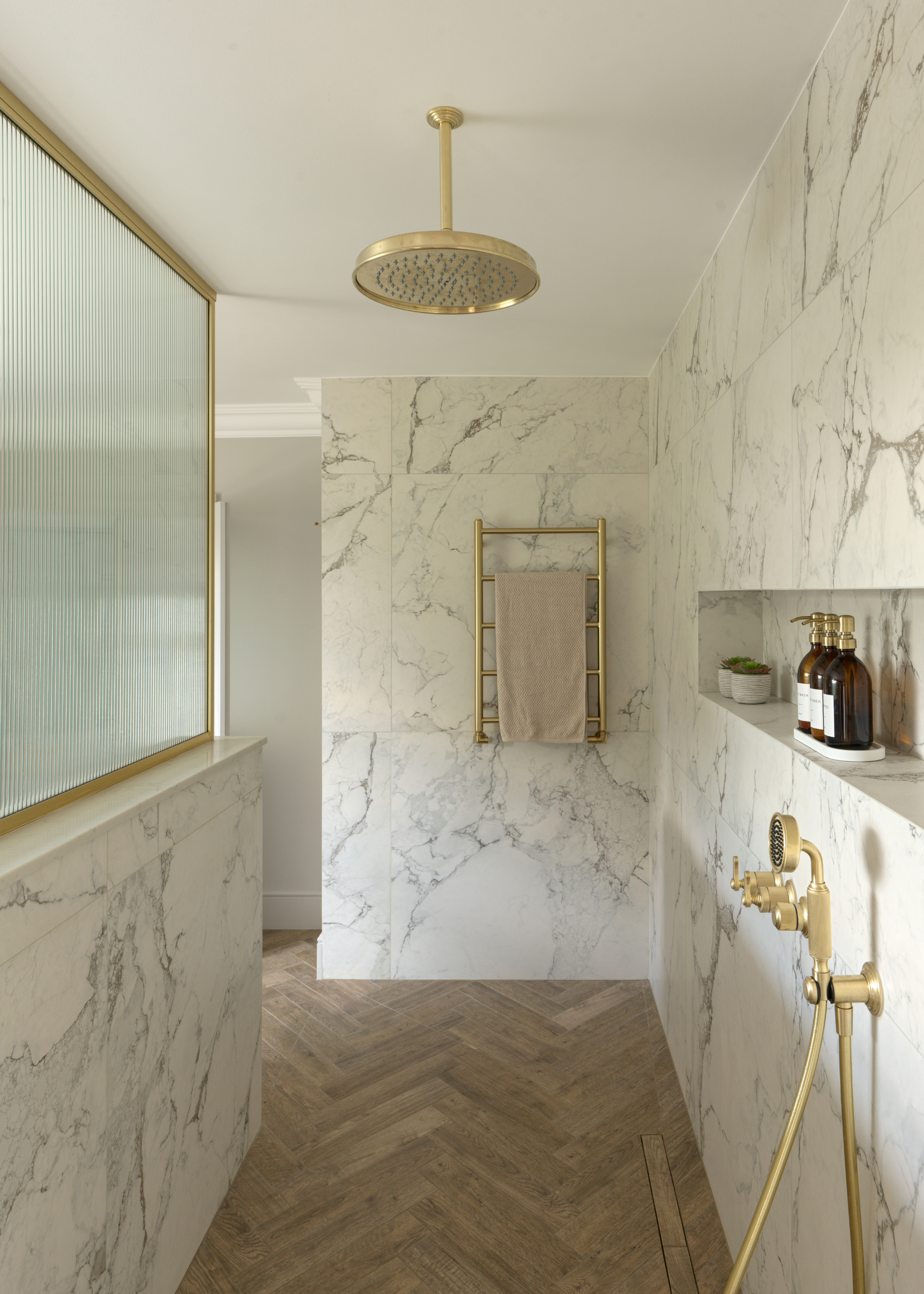 walk-in shower with herringbone floors and large format marble tiles