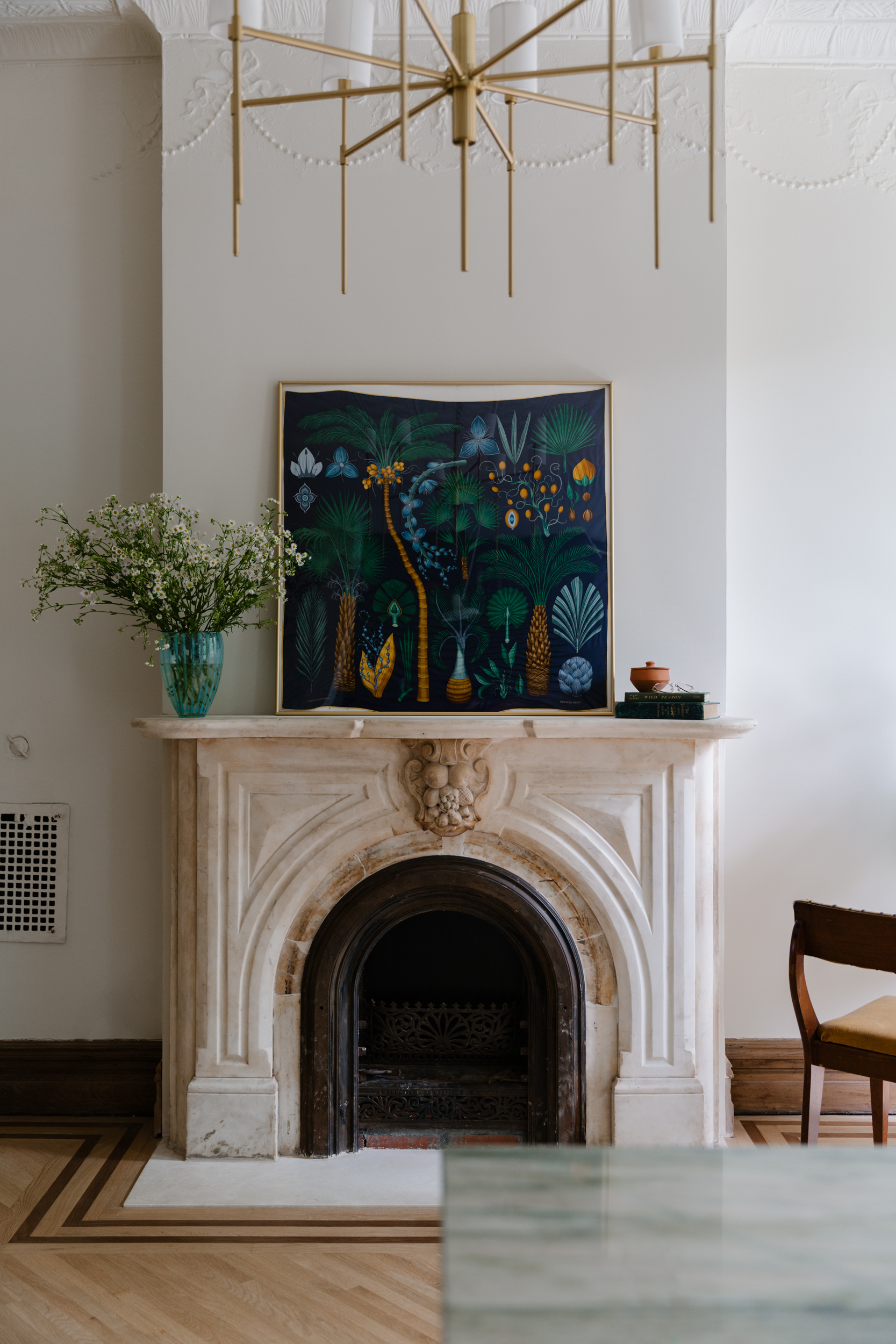 Ancient Brownstone Living Room Interior with a marble fireplace cover and vintage-inspired chandelier that hangs above.