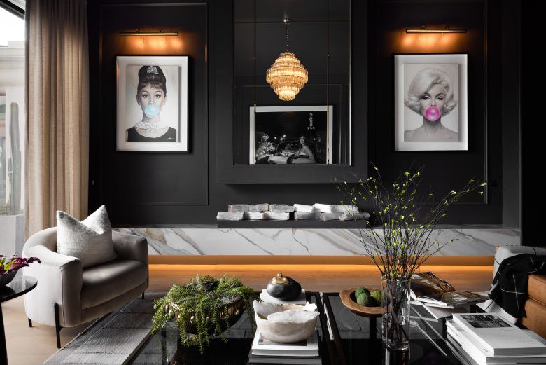 A living room with a marble stove, black walls and decor with Audrey Hepburn and Marilyn Monroe.