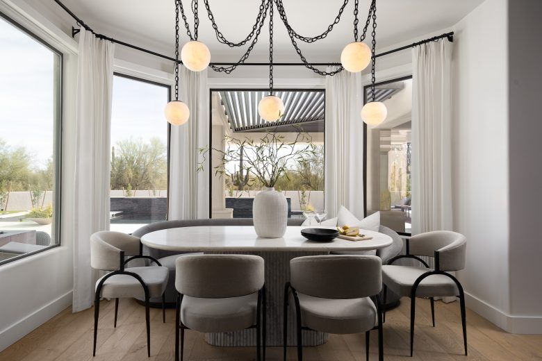 A breakfast corner with large windows, white walls and hanging trailer lights.