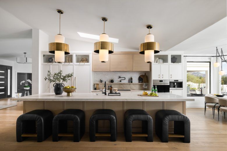 A kitchen with light wooden cupboards and black barhoses.