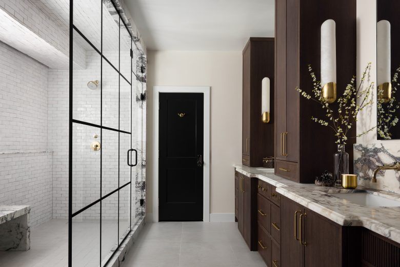 A bathroom with a walk in a tiled shower on the left and dark cupboards and white worktops on the right.