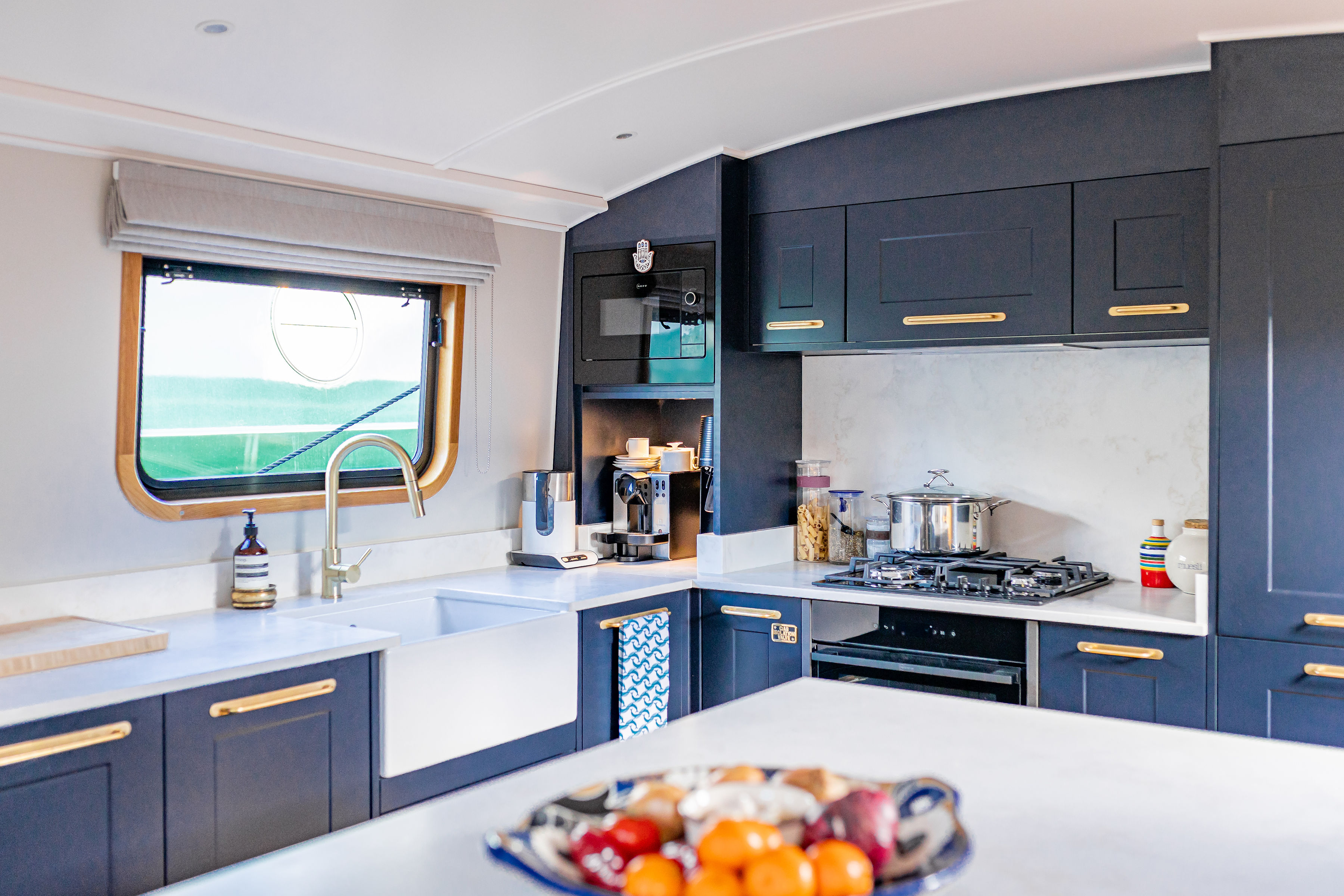 The open gallery of the southern Belle, a 73 -foot long -haul boat, the dark blue cupboards, a farmhouse and a gas stove shows.