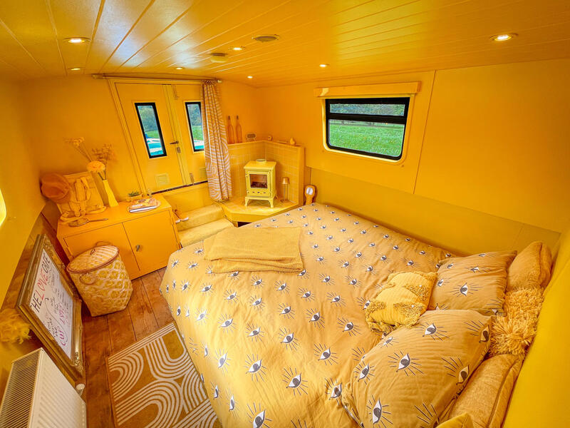 The interior of a yellow boathouse with a yellow bed and white panel sign.