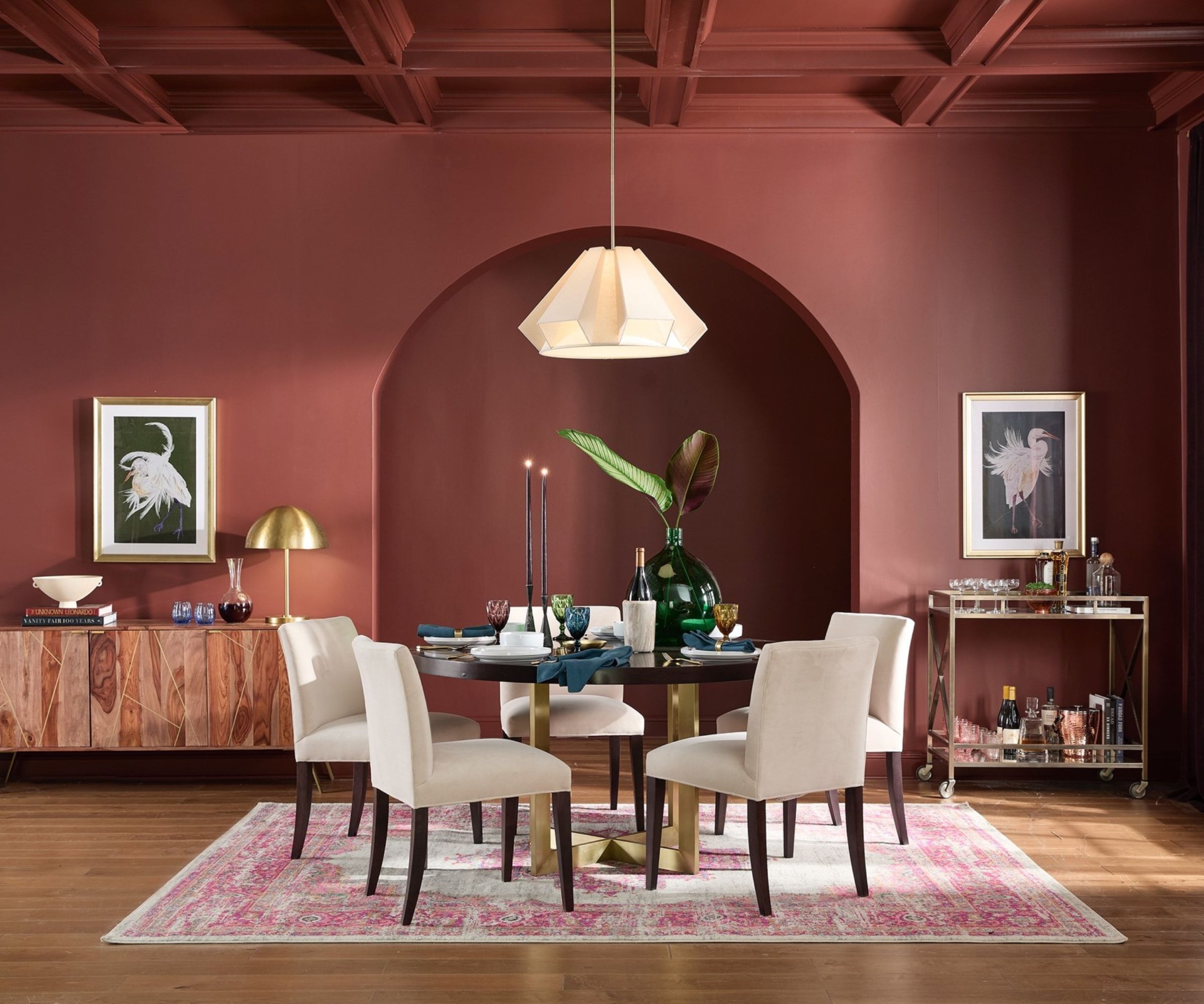 Mahogany red malt dining room with a vaulted corner, wood and gold table with boucle chairs, console and bar wagon