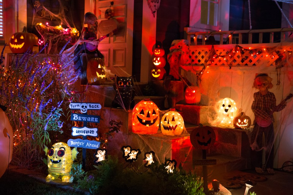 A house that was decorated for Halloween with illuminated pumpkins, skeletons, instruments, ghosts and spider websites.