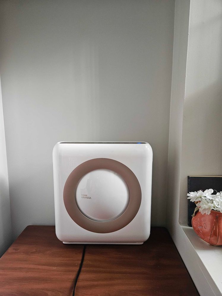 Coway Airmega air purifier on a wooden table.