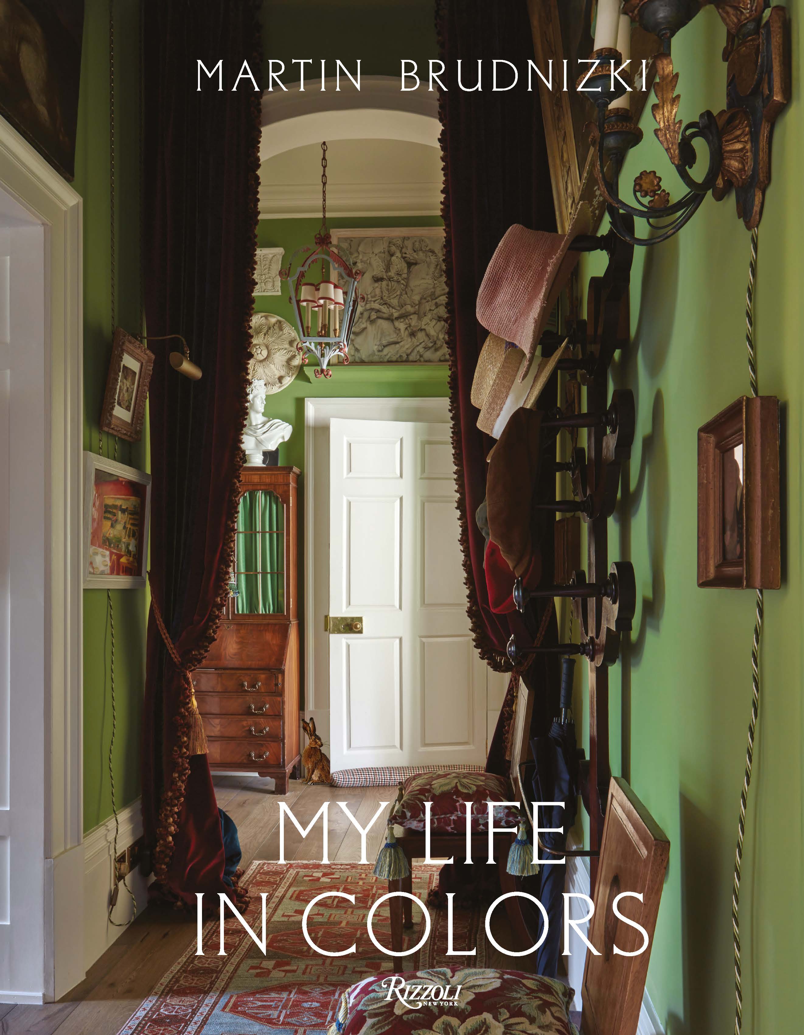 Book cover for Martin Brudnizki's "My life in colors," With a hallway with green walls, red velvet curtains, a secretary desk and a catastack with hats.