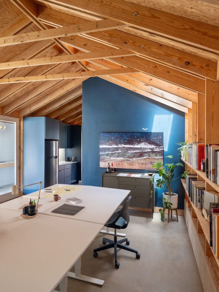 Deep blue cuisine and the bathroom external, which contrasts a exposed wooden structure