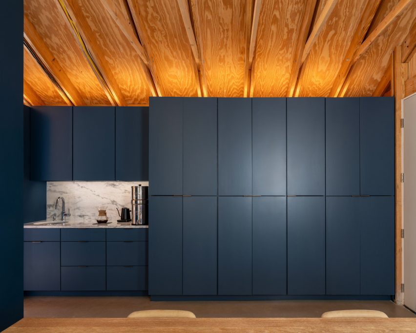 Minimally detailed kitchen and storage units under a wooden ceiling