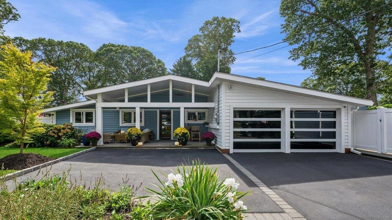 The Massapequa home for sale features outdoor living space and one-way glass garage doors