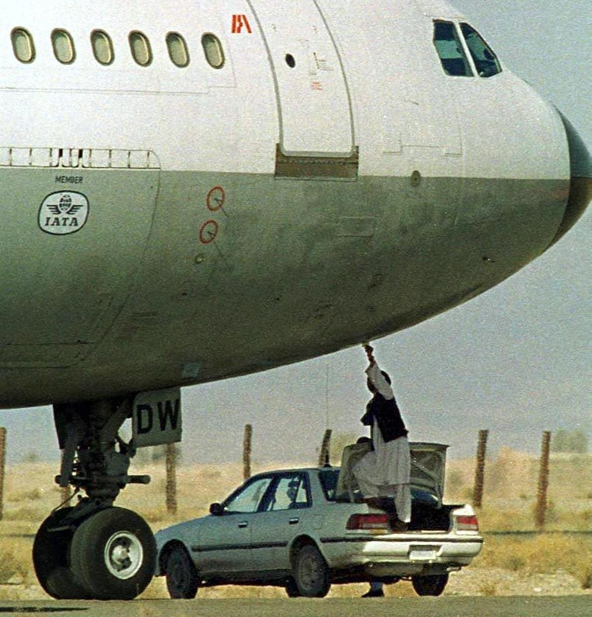 A Taliban security officer reaches out of the trunk of a car to collect a paper from the hijacked Indian Airlines flight IC-814.