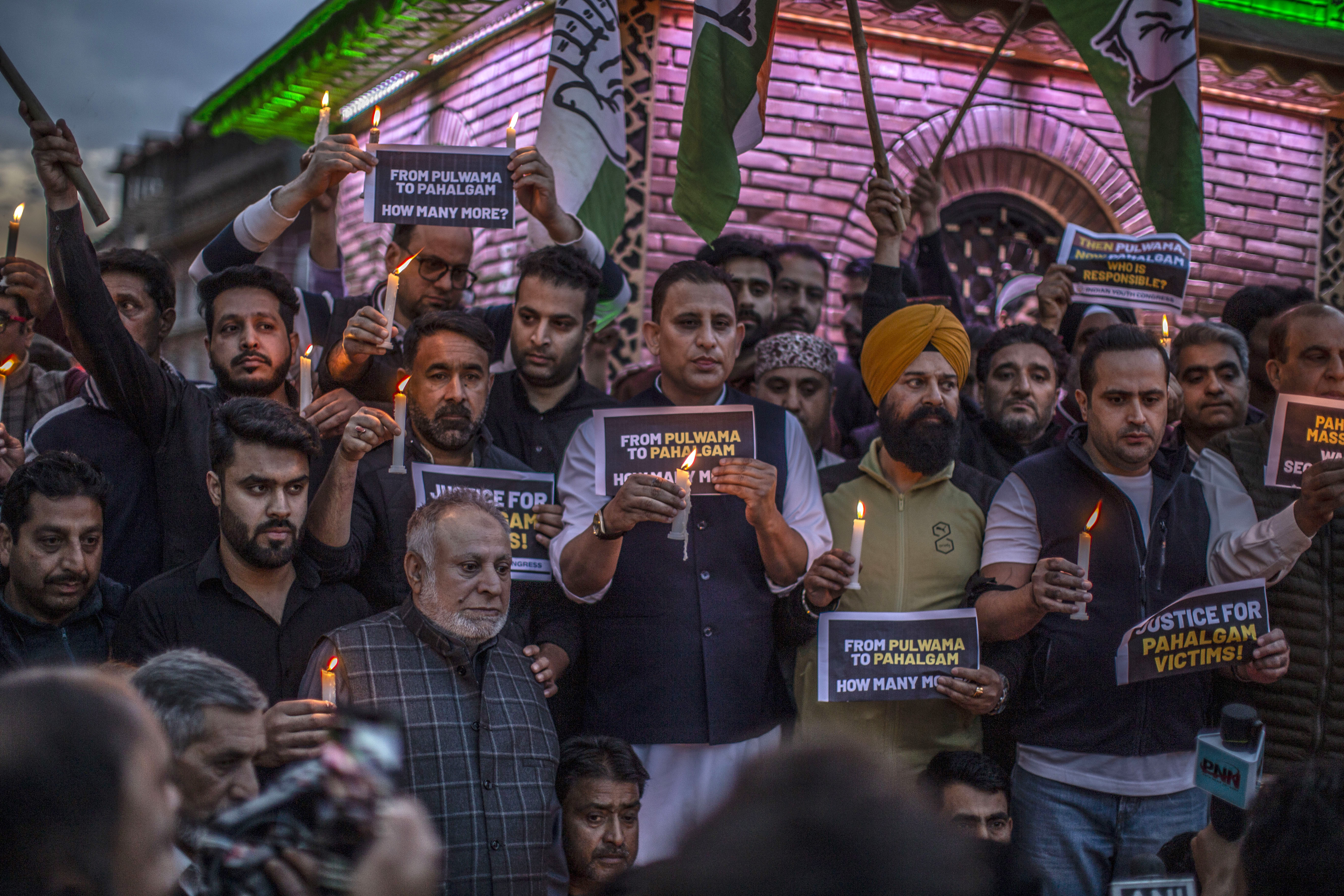 Kashmiri traders hold a candlelight vigil in Srinagar, India, holding signs reading 