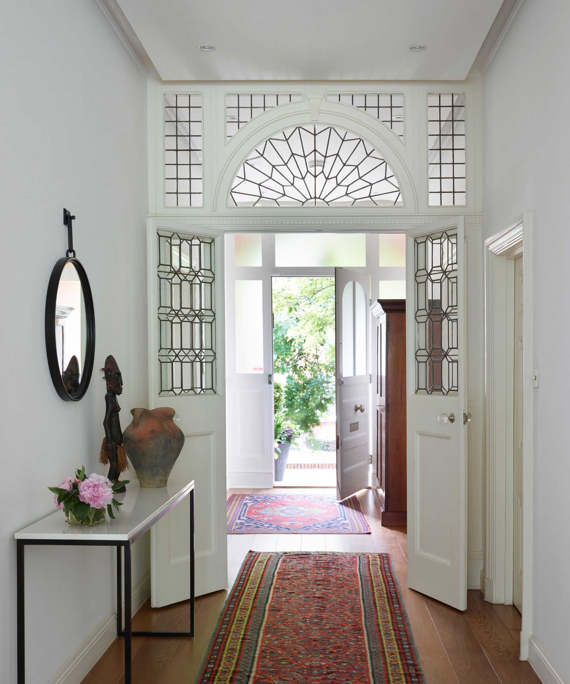 Hallway with glass door, wooden floor and vintage carpets