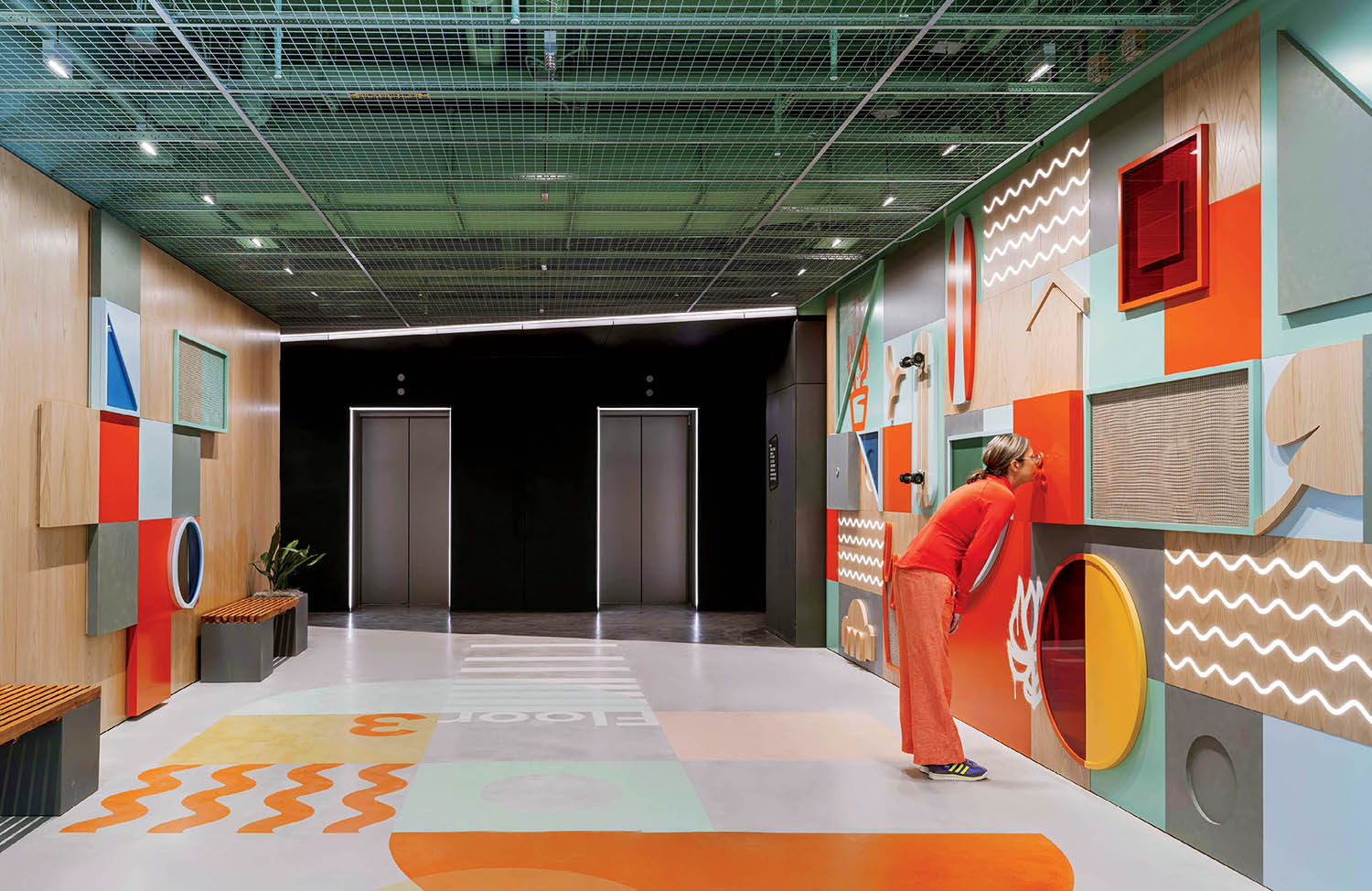 A woman walks through a brightly painted hallway.