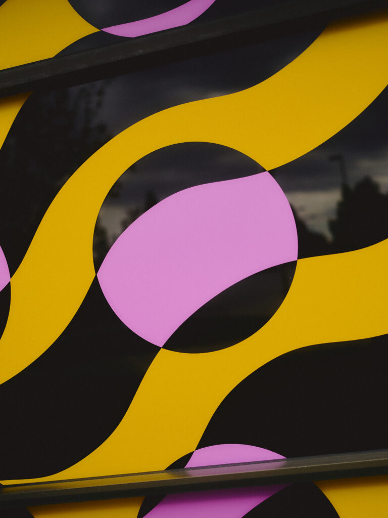Close-up of a window picture with yellow wavy lines and pink circles on a dark background.