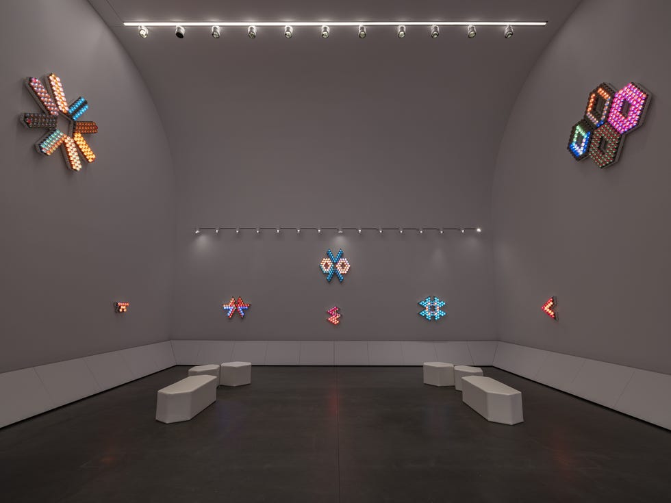 Art installation with illuminated decorative shapes on the walls of a gallery.