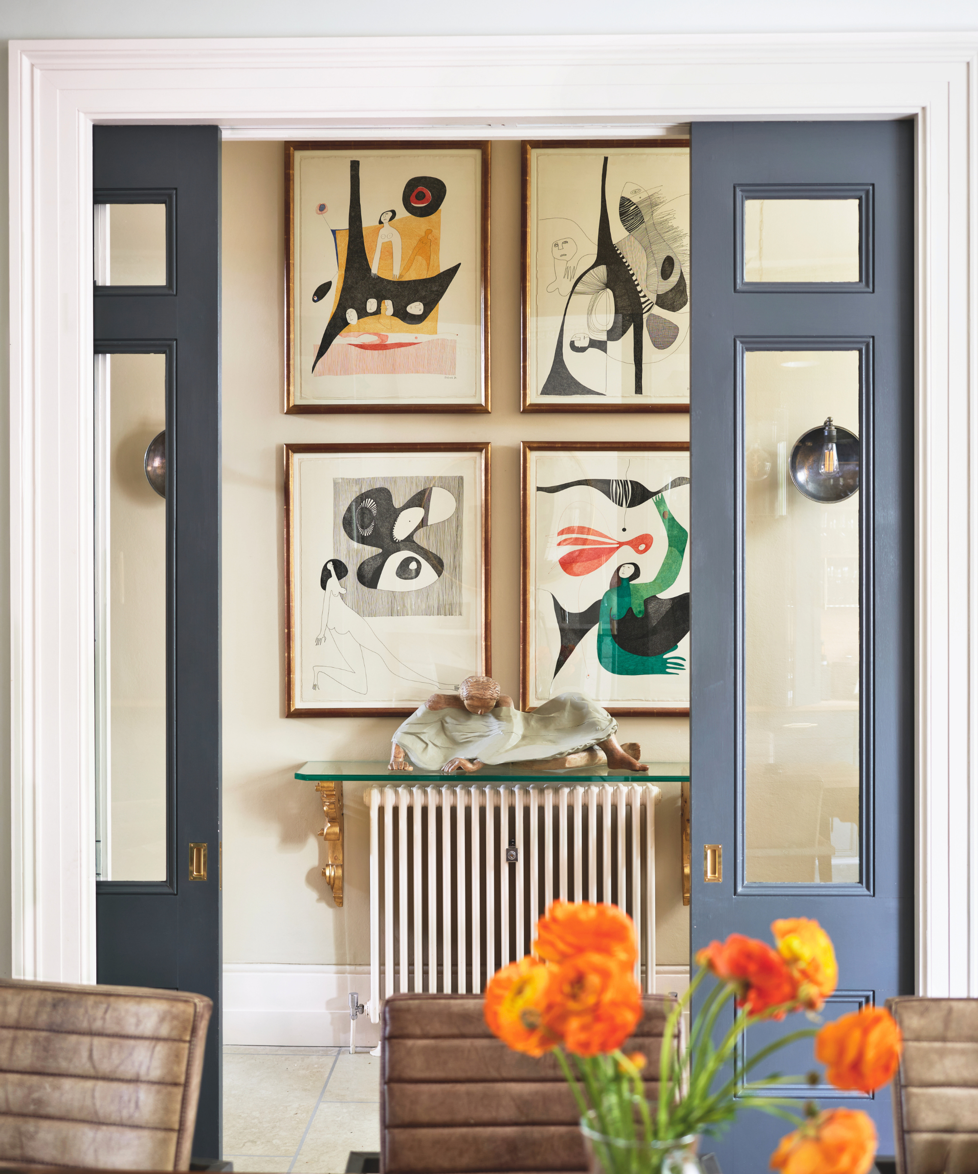 a room with pocket doors painted slate blue. There are four pictures hanging on the wall in the hallway behind the doors