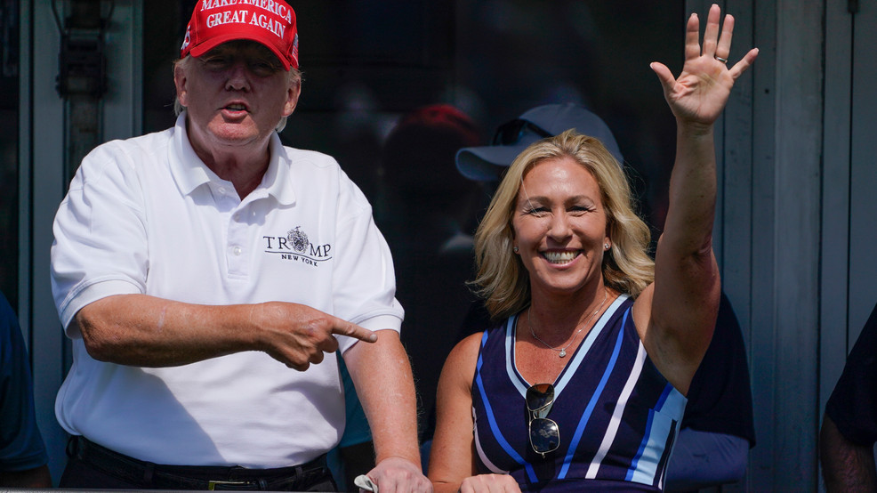 FILE - Rep. Marjorie Taylor Greene, R-Ga., waves as former President Donald Trump points at her as they look over the 16th tee during the second round of the Bedminster Invitational LIV golf tournament in Bedminster, NJ, July 30, 2022. (AP Photo/Seth Wenig, File)