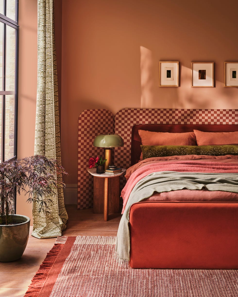 a bedroom with a red velvet bed, a checkered headboard, a side table with a lamp on it and a red carpet