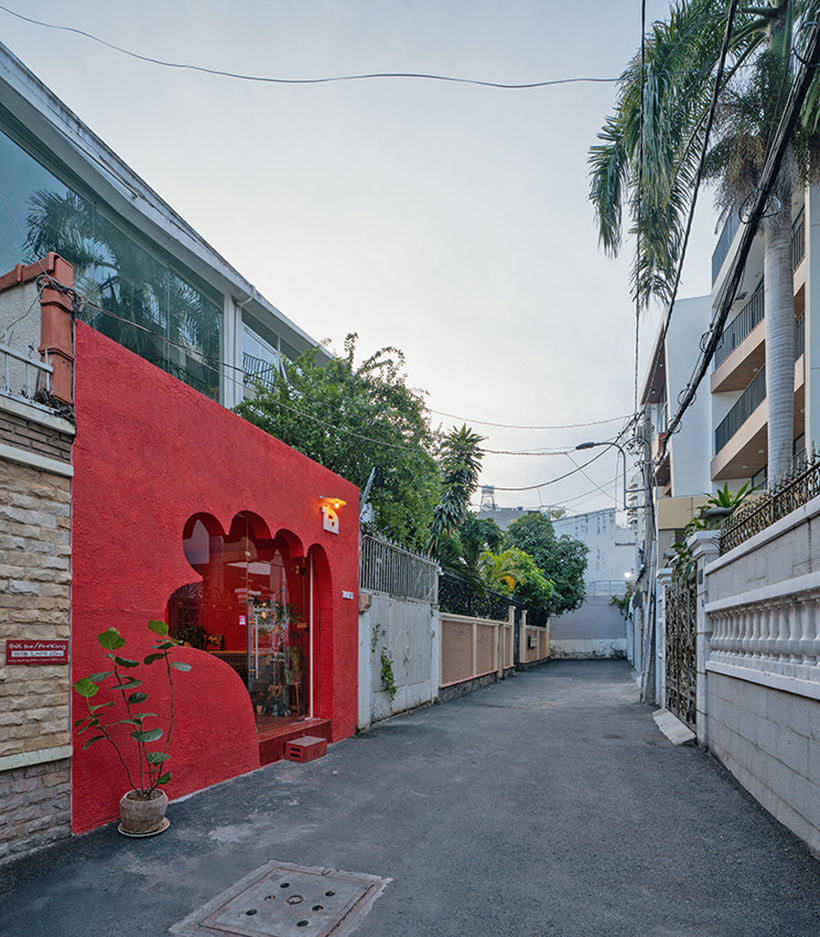 The red facade of the café creates an inviting hand-shaped entrance in Vietnam