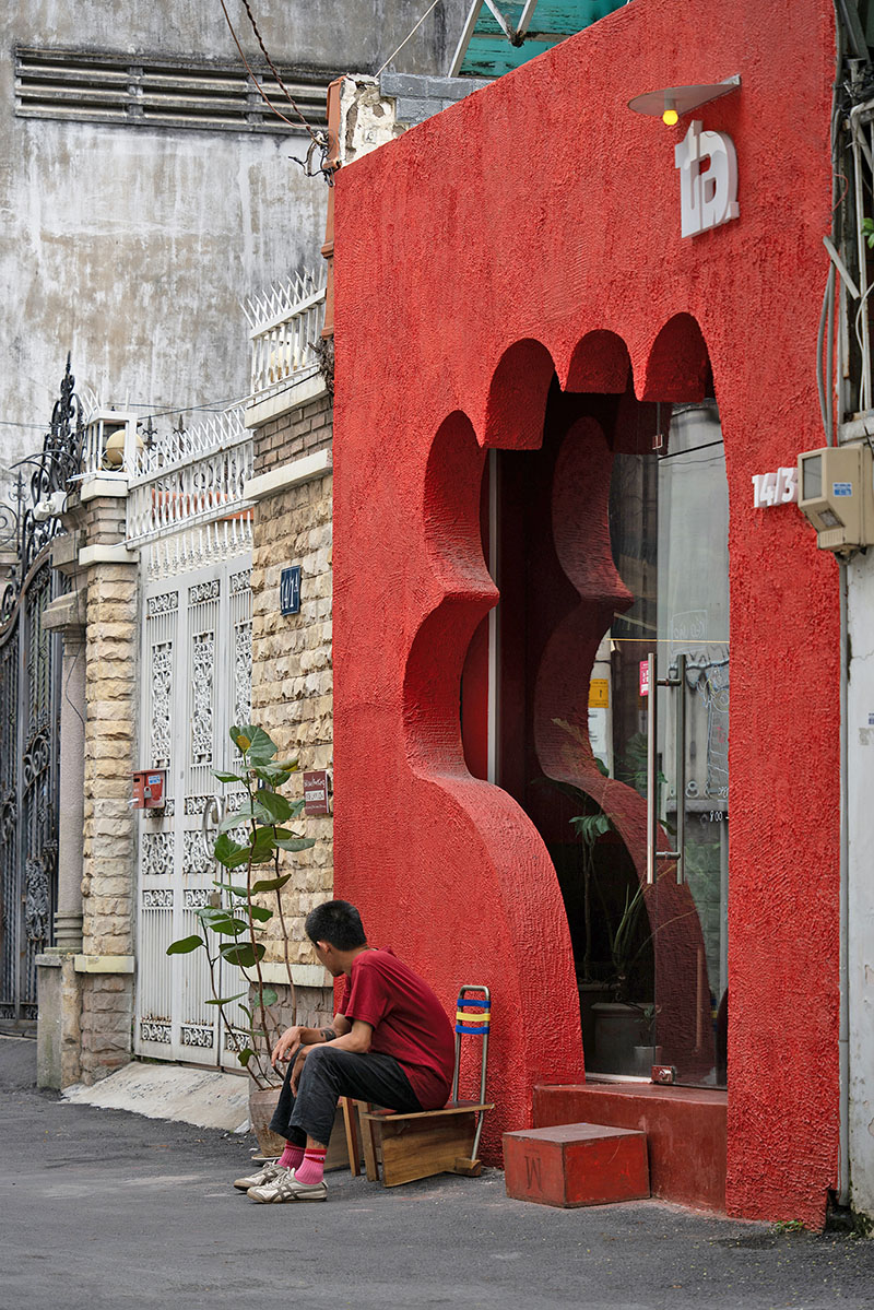 The red facade of the café creates an inviting hand-shaped entrance in Vietnam