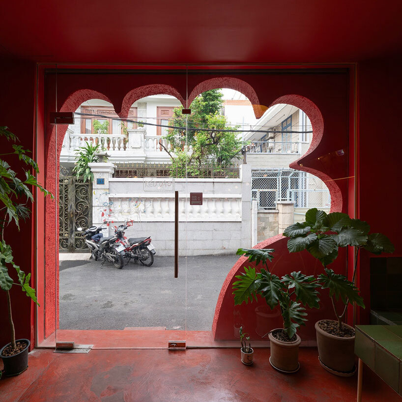 The red façade of the café creates an inviting, hand-shaped entrance in Vietnam