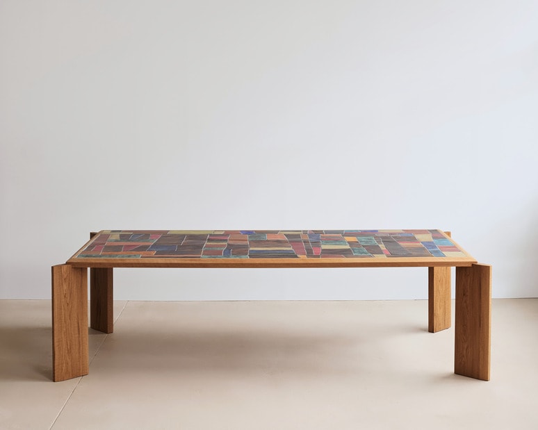 Wooden table with a colorful geometric pattern on the tabletop against a plain white background.