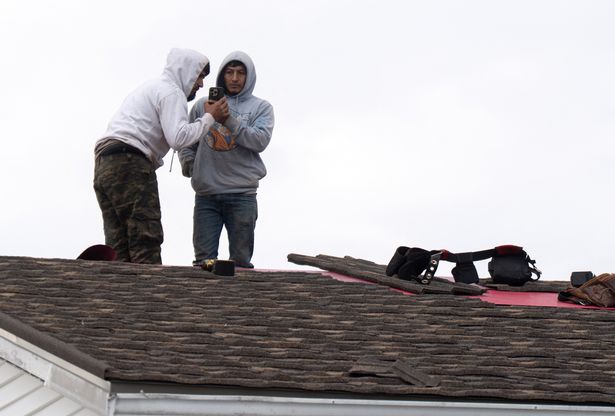 Construction workers talk on a cell phone after U.S. Customs and Border Patrol (CBP) agents arrested colleagues from a rooftop in Kenner, Louisiana