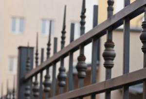 Steel fence with a house in the background.